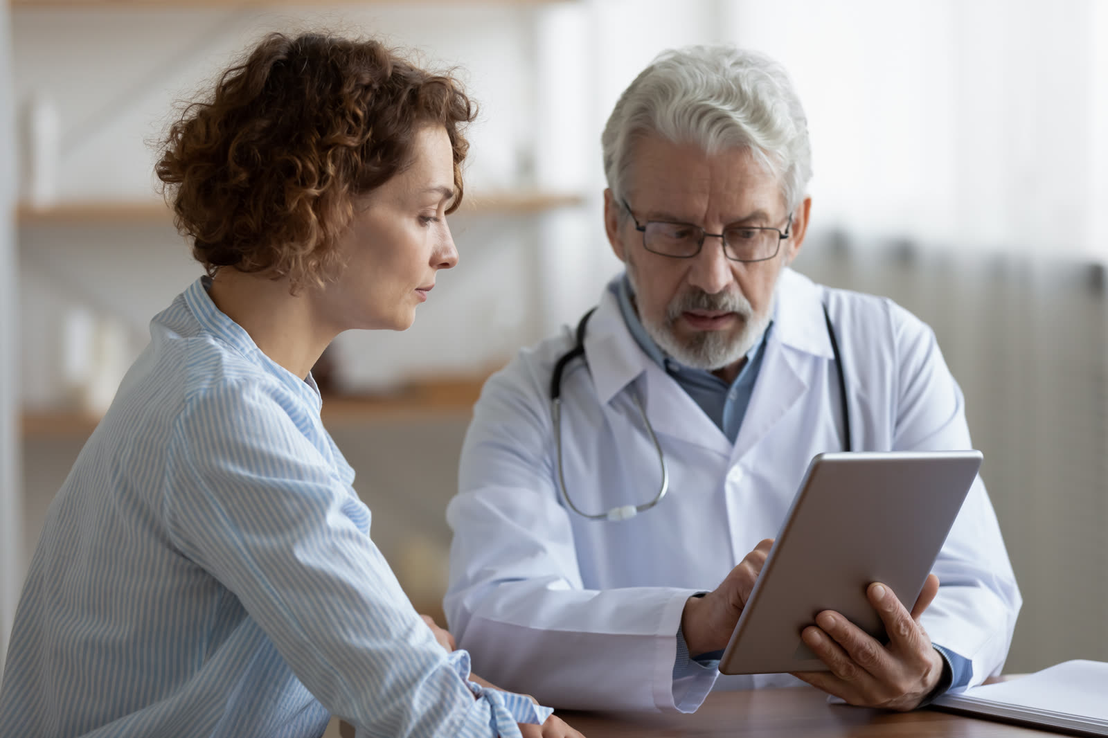 Médico mostra resultados no tablet para a paciente