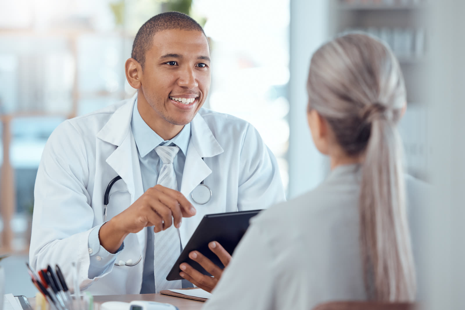 Médico conversa com a paciente segurando um tablet